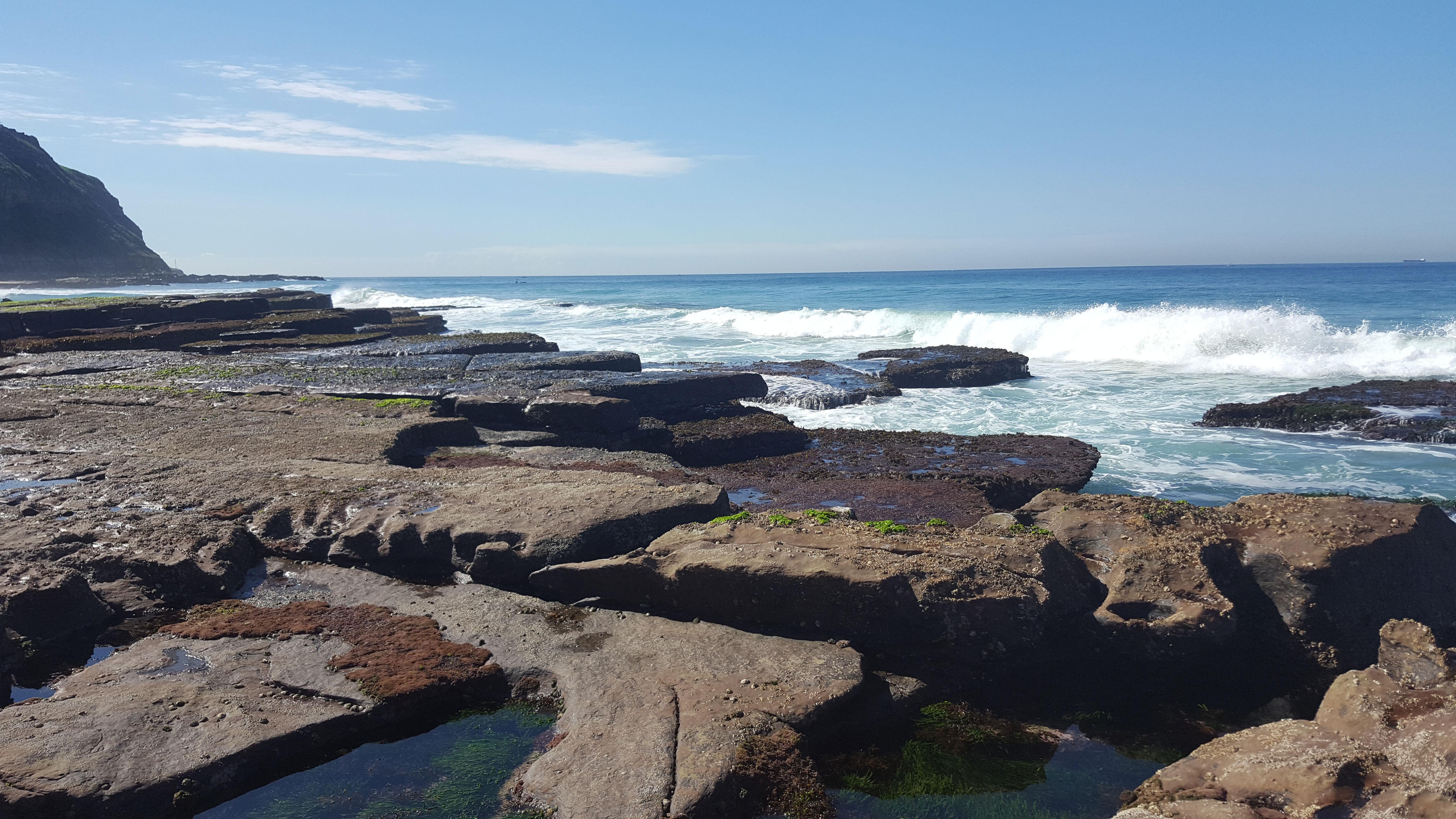 waves breaking over rocks with water pools in the foreground at Bar Beach Newcastle