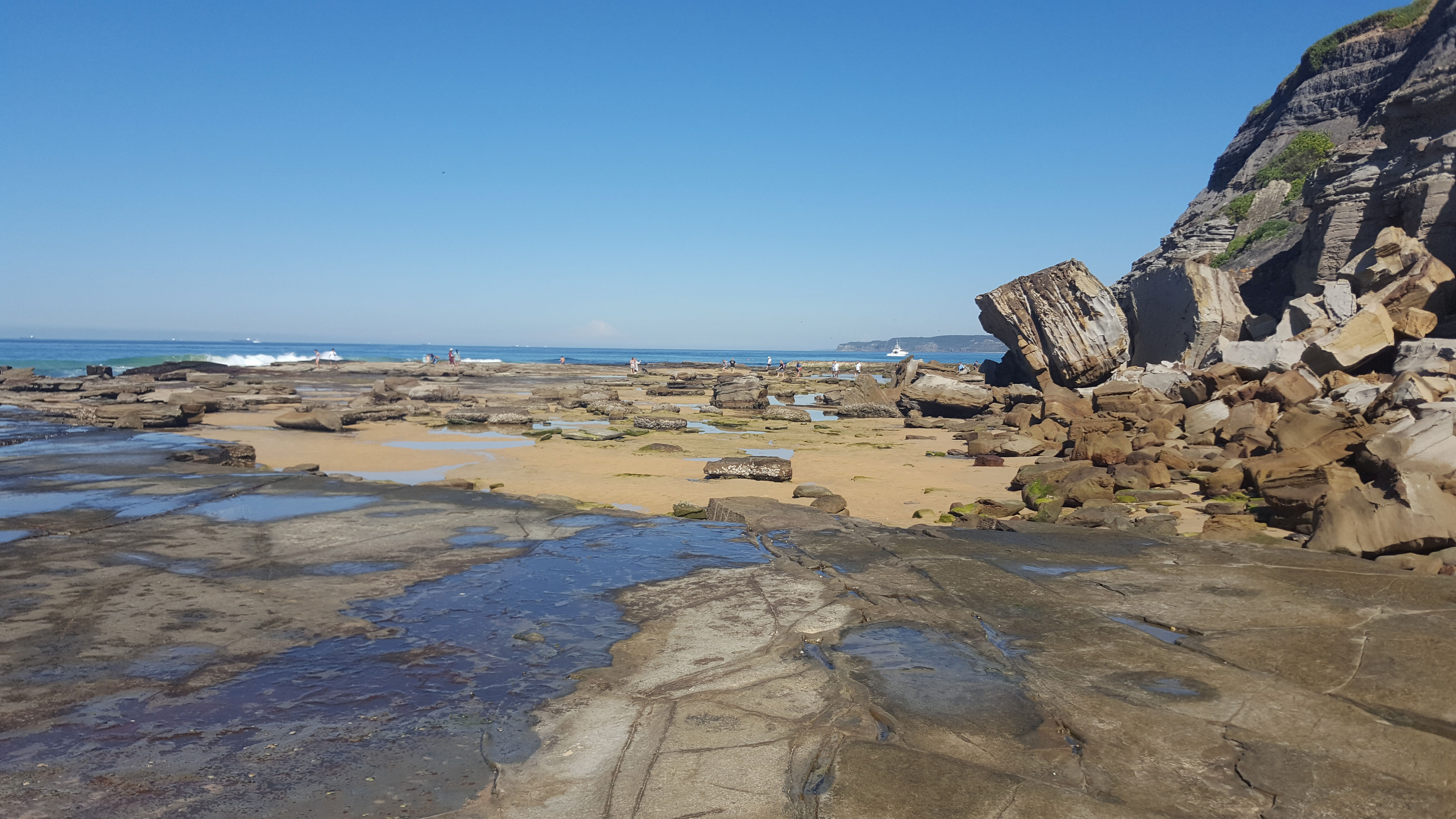 waves breaking over rocks with water pools in the foreground at Bar Beach Newcastle