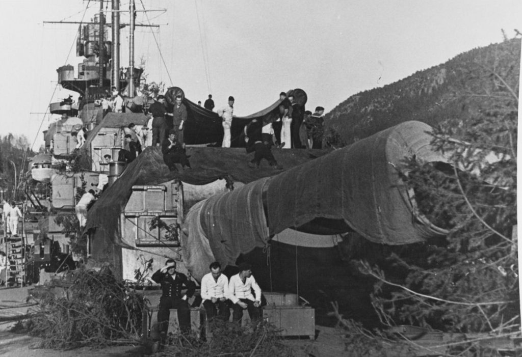 Crewmen camouflaging the ship, while others relax by the after 380mm gun turret, as she lay in the Flehke Fjord, Norway, circa 1942