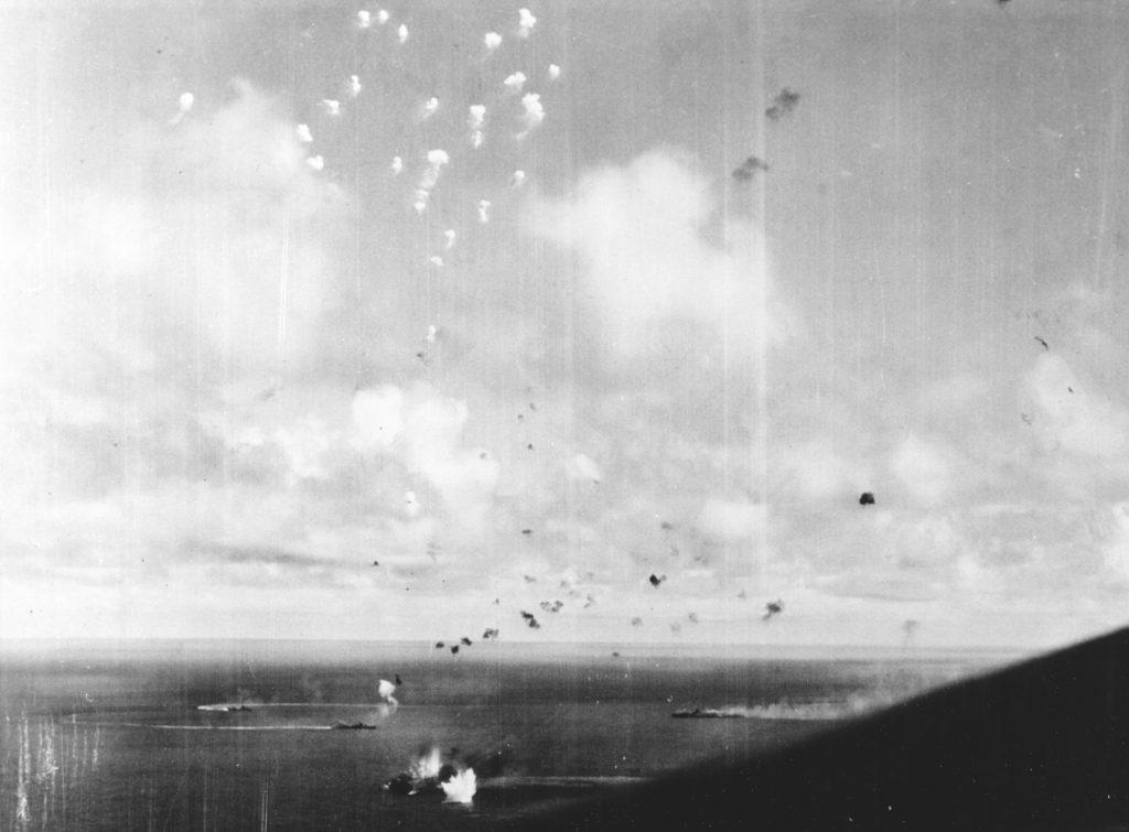 Bombs are falling Zuihō, in lower left center. The large carrier Zuikaku is burning and apparently dead in the water in the right center distance