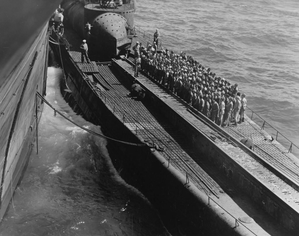 Japanese crew mustered on deck after surrender. Note US sailors with guns