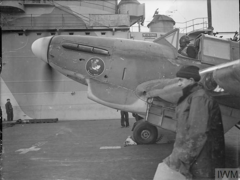 A Fairey Fulmar warming up on the flight deck of HMS Victorious. Note the Donald Duck painted on the nose of the plane.