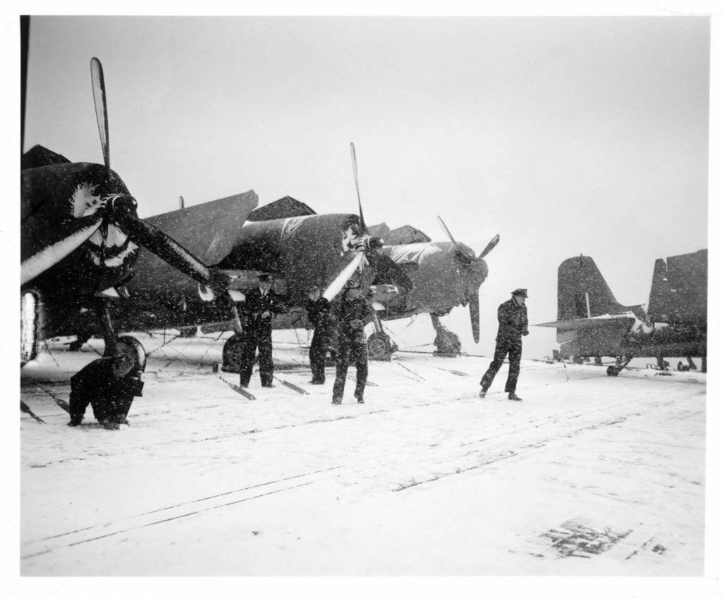 Snowball fight on the deck of HMS Emperor in front of Hellcat fighters