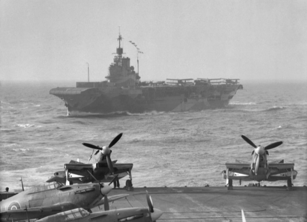 12 August 1942 HMS Indomitable maneuvering astern of HMS Victorious.