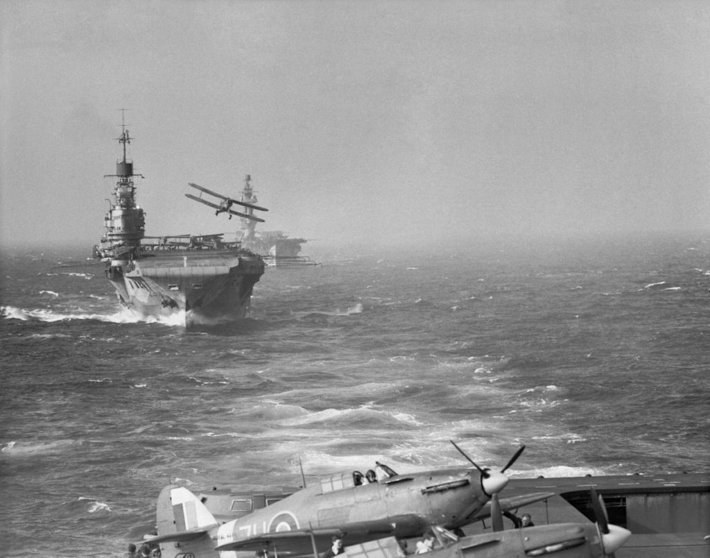 Seen from the flight deck of HMS Victorious, a Fairey Albacore takes off from HMS Indomitable