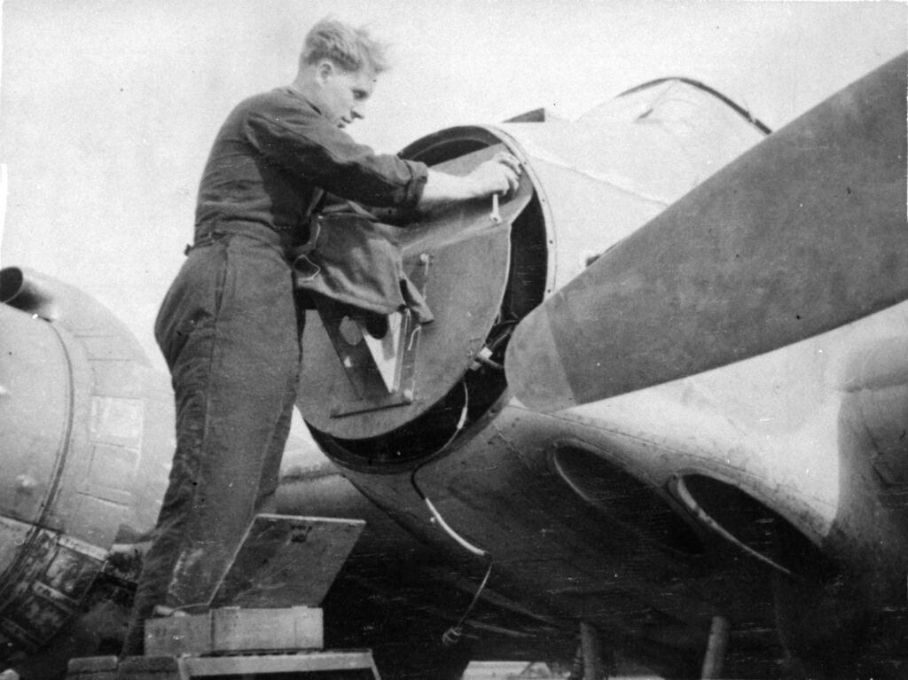 A No. 489 Squadron ground crew member working on the nose mounted armour plate of a Bristol Beaufighter