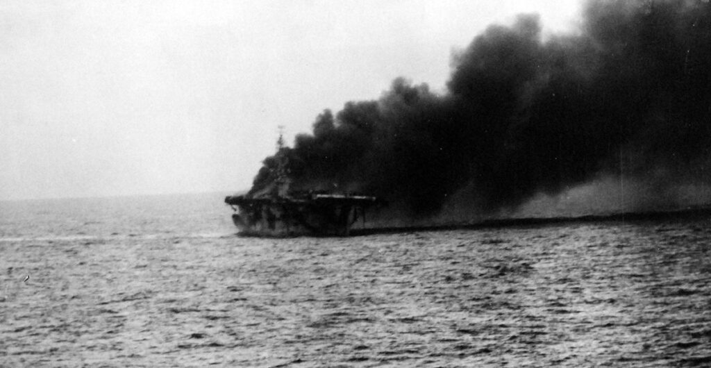 USS St. Lo (CVE-63) burns after being hit by a Kamikaze on 25 October 1944 taken from USS Kalinin Bay (CVE-68)