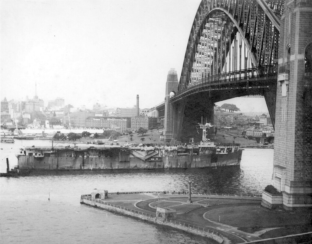 HMS Vindex passing under the Sydney Harbour Bridge with 300 ex-prisoners of war returning home