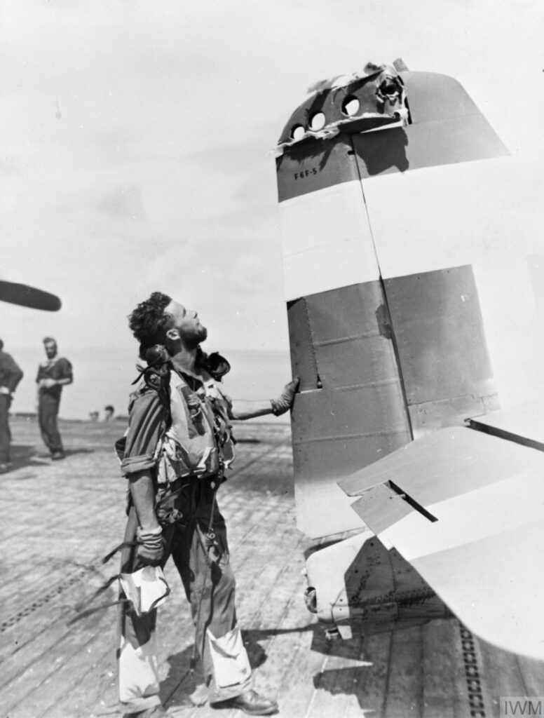 Grumman Hellcat Mk.II Royal Navy FAA 808 NAS SubLt RJ. Foxley examines his damaged aircraft May 1945